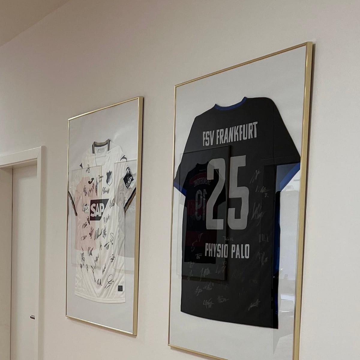 Gerahmte, signierte Mannschaftstrikots im Flur der Praxis – darunter ein Trikot des FSV Frankfurt mit dem Aufdruck PhysioPALO